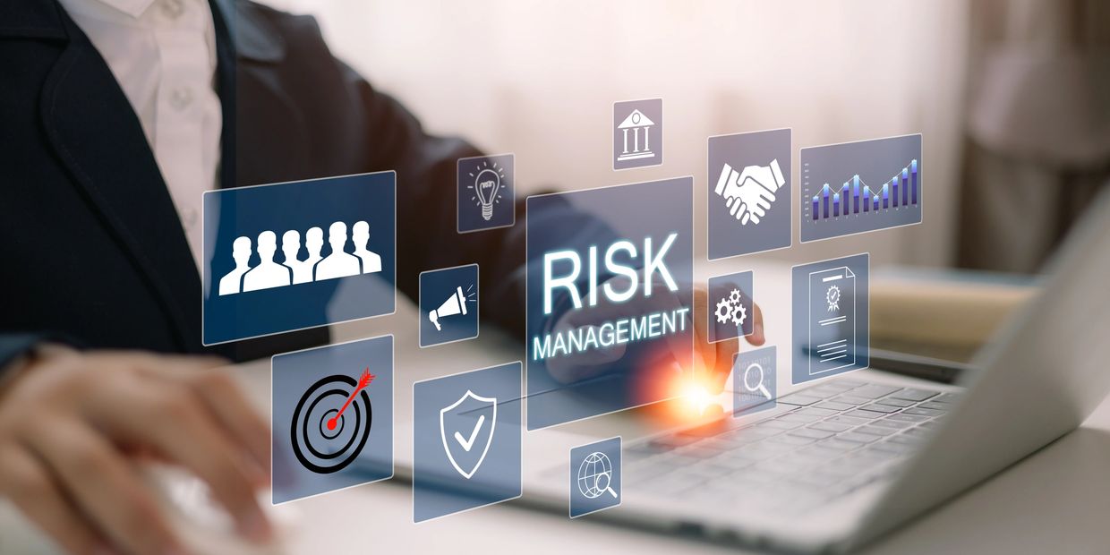 Business professional working on risk management on a laptop with digital icons.