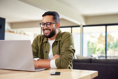 Man smiling while working on laptop at home.