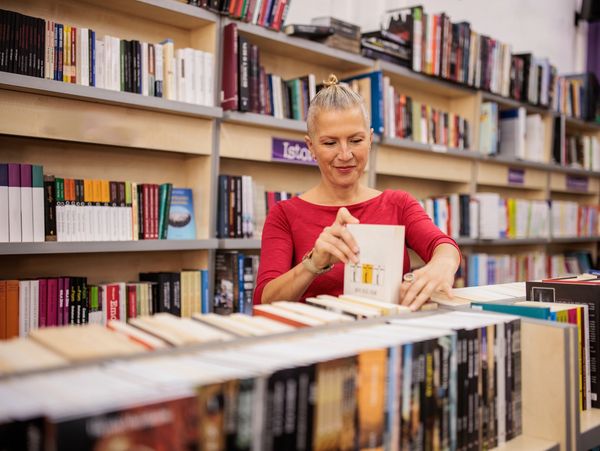 A woman browsing books in a bookstore with shelves full of books.