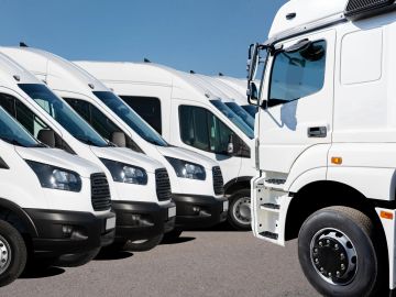 Fleet of white delivery vans and a truck lined up outdoors.