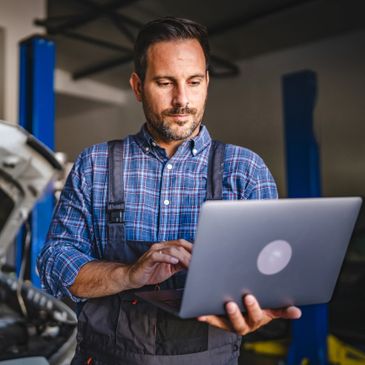 Mechanic using a laptop in an auto repair shop.