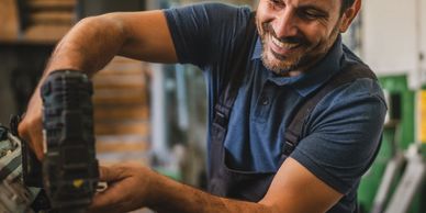 Smiling man fixing a piece of equipment.