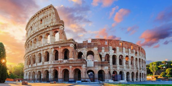 The Colosseum in Rome at sunset with a colorful sky.