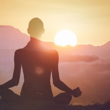 Person meditating at sunrise.