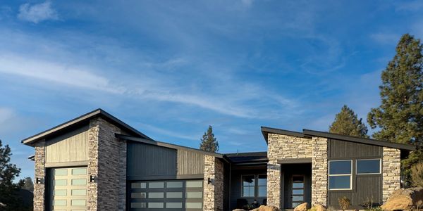 Modern house with stone and wood exterior under a blue sky.
