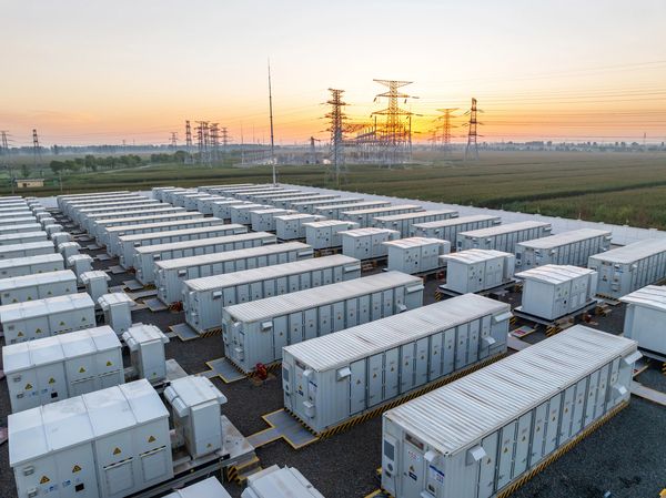 A large battery storage facility with rows of white containers at sunset.