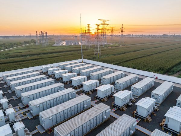 Battery storage units at an energy facility during sunset.