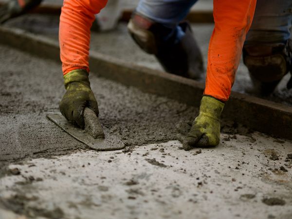 Construction worker smoothing wet concrete with a trowel.