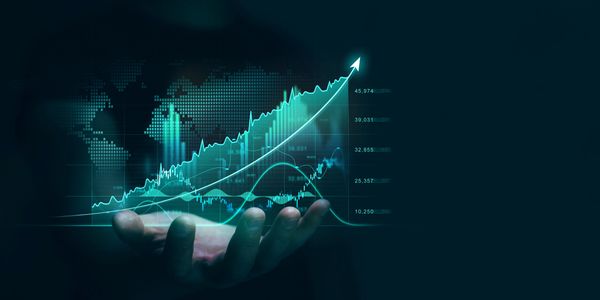 Hand holding a glowing digital graph with rising financial data and a world map.