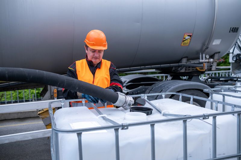 A technician transfers oil from a tanker into a 1000-liter IBC Bulk Container.