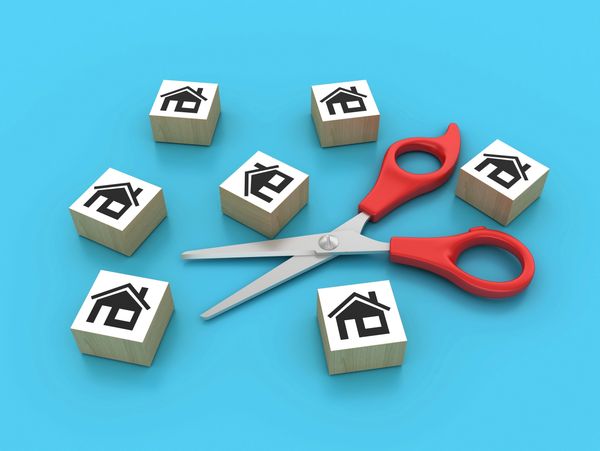 Scissors surrounded by house icon blocks on a blue surface.