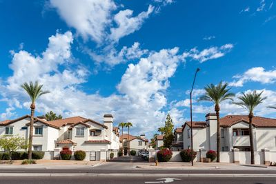 Gated community with palm trees under a bright blue sky.