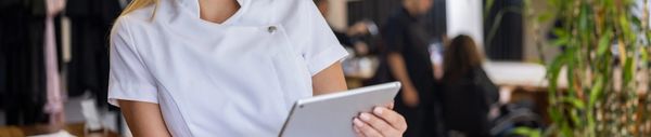 Smiling person in white uniform holding a tablet.