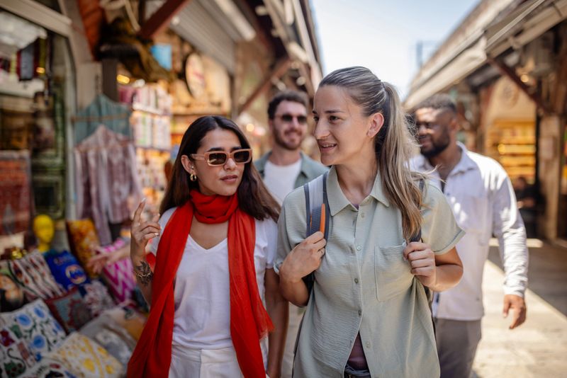 Friends laughing and enjoying their time as they explore an urban market filled with vibrant stalls, depicting a day of leisure and communal happiness in a lively setting.