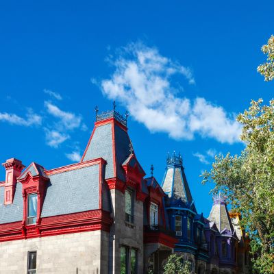 Maisons colorées avec toits pointus sous un ciel bleu clair.