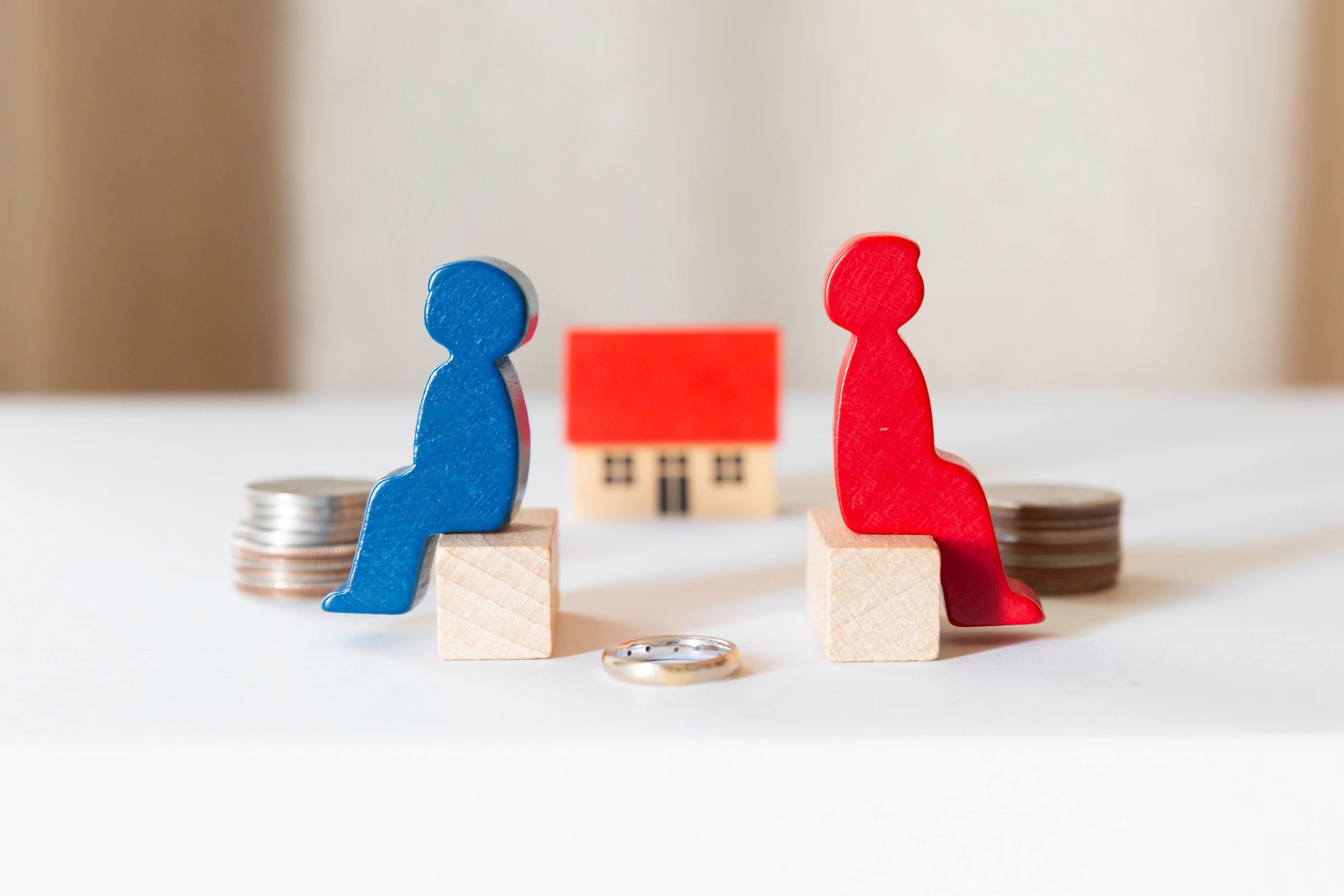 Blue and red figures sitting apart with a house and wedding ring between them.