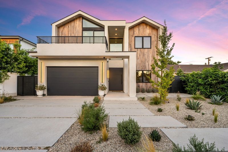 Modern two-story house with a wooden facade illuminated by the sunset