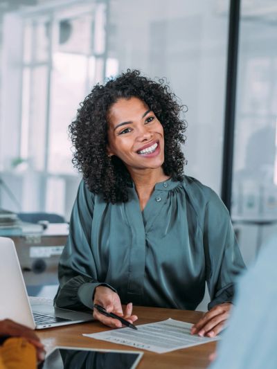 Smiling woman in office setting reviewing documents.