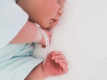 Sleeping newborn baby with hospital wristband.