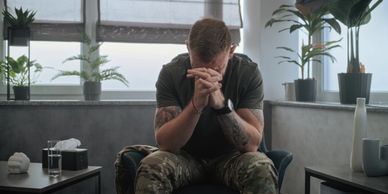 A man sitting with his head down, looking distressed.