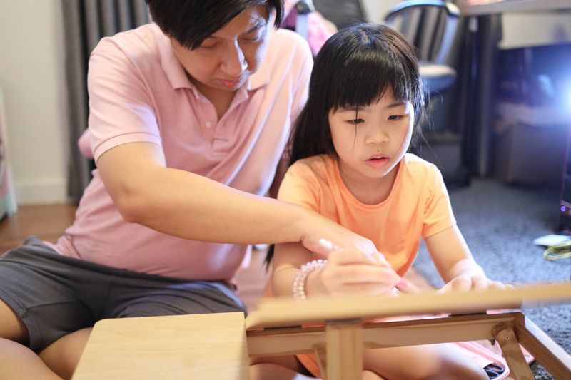 The East Asian father and daughter spending time together in the house.