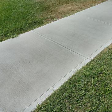 Clean concrete sidewalk bordered by green grass.