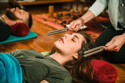 Person receiving tuning fork therapy while lying down with eyes closed.