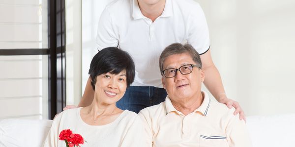 Smiling family with gifts and flowers on a white couch.