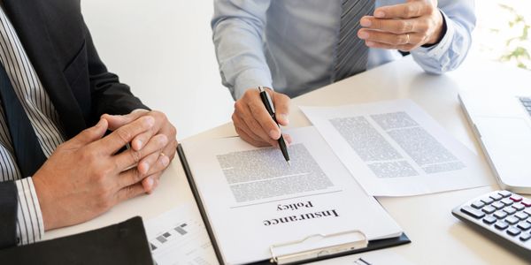 Two professionals discussing an insurance policy document at a desk.