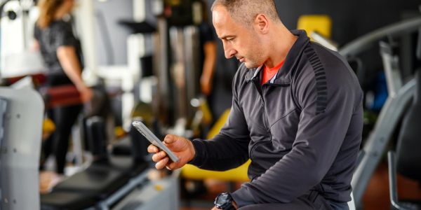 Man in workout gear checking phone at the gym.