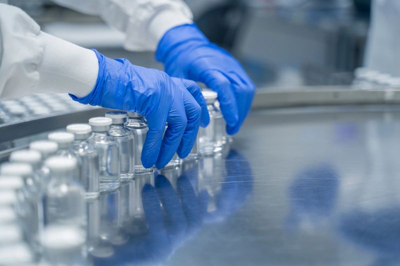 Detail of hands working in pharmaceutical factory manufacturing sterile bottles