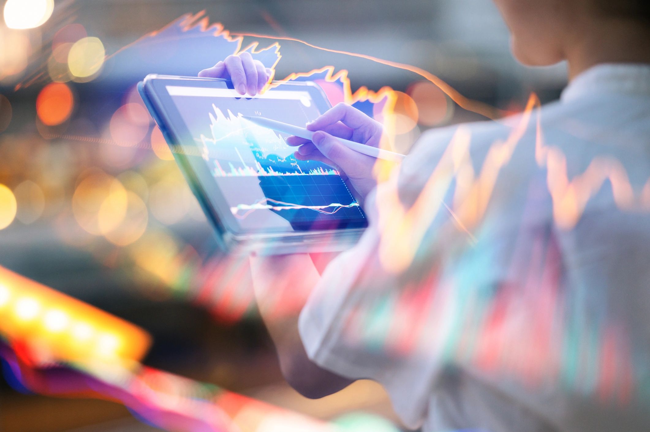 Person analyzing financial data on a tablet with dynamic charts overlay.