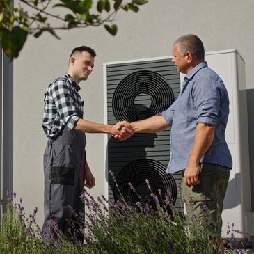Technician and homeowner shaking hands outside near an air conditioning unit.