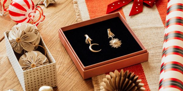 Elegant gold earrings in a gift box surrounded by festive wrapping items.
