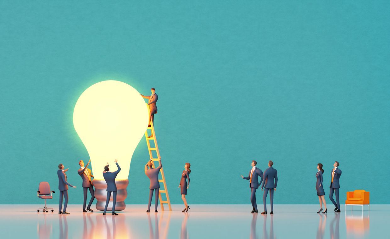 Business team collaborating around a giant glowing light bulb symbolizing a big idea.