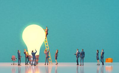 A group of people standing around a light bulb.