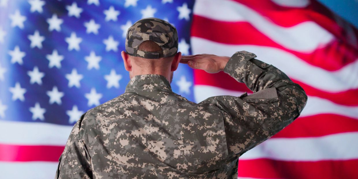 A soldier saluting the American flag in uniform.