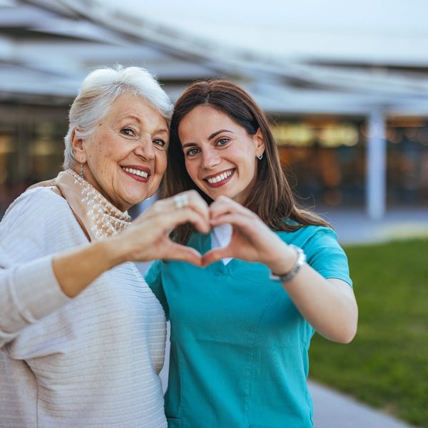 A woman and an older lady making heart shapes with their hands.