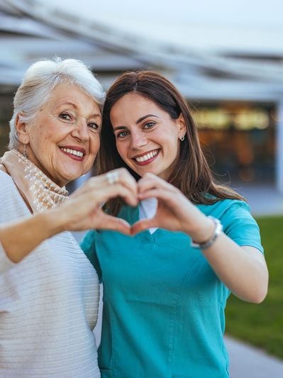 A woman and an older lady making heart shapes with their hands.