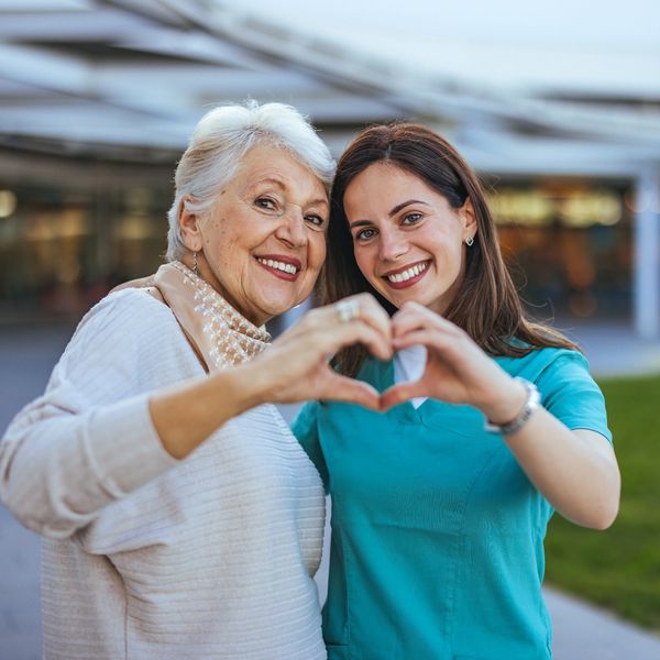 Older woman and young woman making a heart with their hands.
