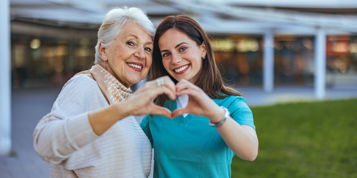 A woman and an older lady making heart shapes with their hands.