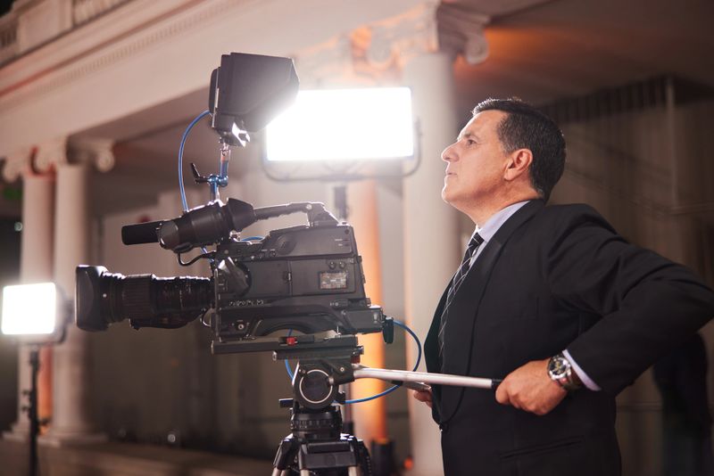 The camera operator, focused and professional in a suit, diligently stream the event, capturing every detail.