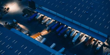 Aerial view of trucks parked at a warehouse loading dock at night.