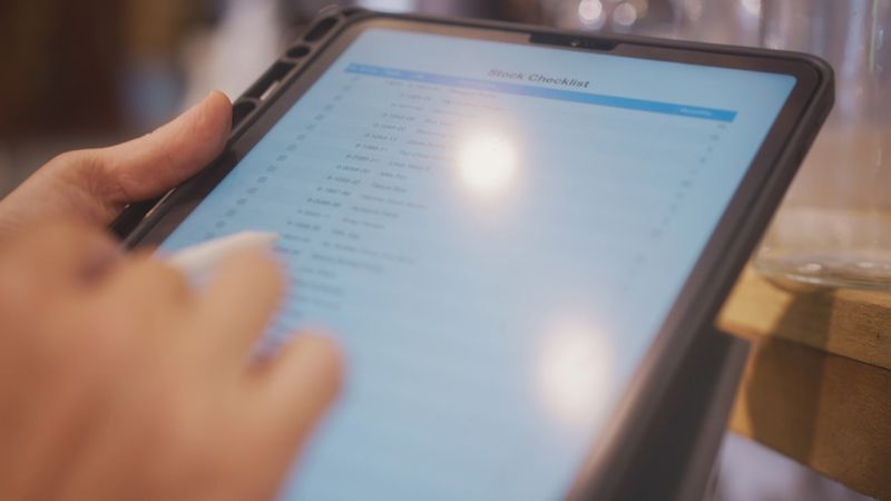 Close-up of a hand using a digital tablet to check the inventory in his home and garden decoration store.