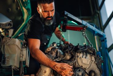 A mechanic repairing a car engine with focused attention.