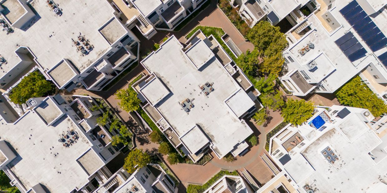 Aerial view of a residential complex with white roofs and greenery.
