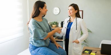 A woman shaking hands with a doctor in a room.