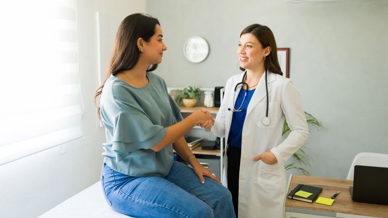 Female doctor happily shaking hands with her hispanic patient after a successful consultation in her office