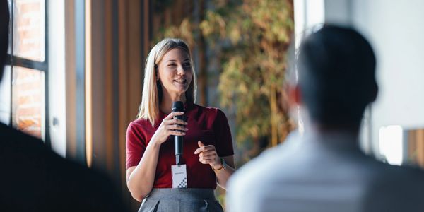 Woman speaker engaging audience with a microphone at a conference.