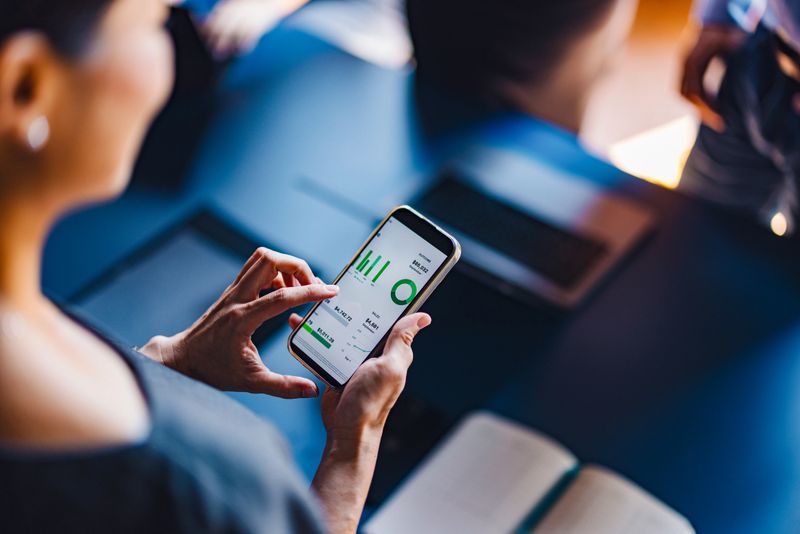 Close-up of a businesswoman using a smartphone to analyze data, showcasing technology and business analysis in a professional setting.